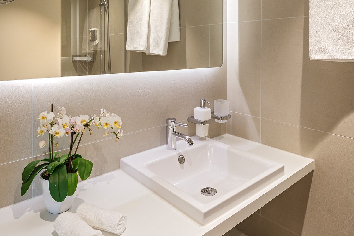 Waschbecken im Badezimmer und Orchideen sowie handtücher im Vordergrund