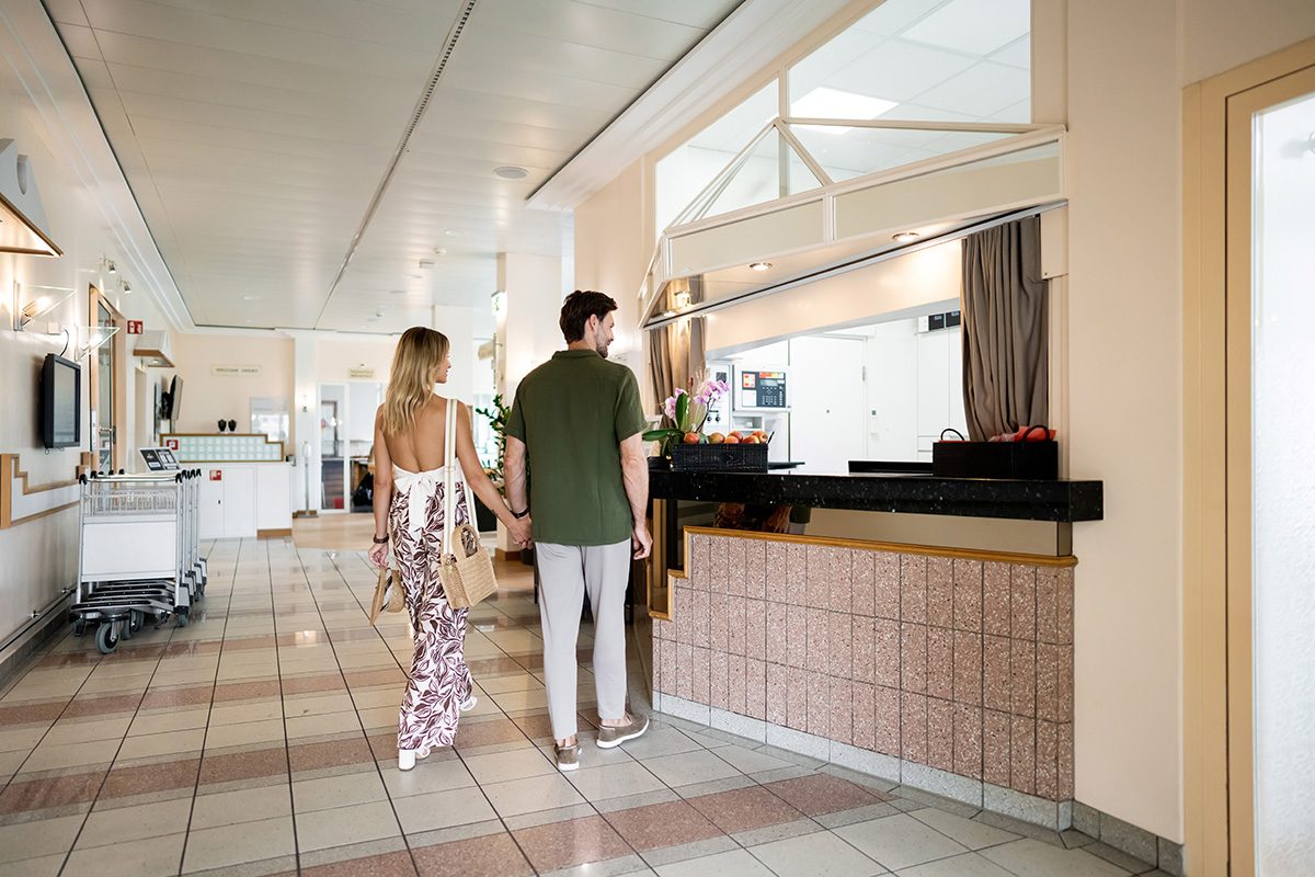 A couple walks through the lobby to the reception desk to check in.